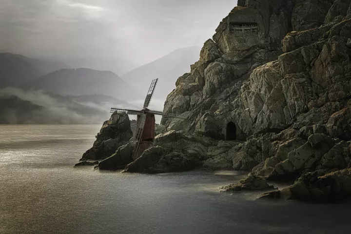 Fata Morgana 008 Une côte rocheus en bord de mer avec un moulin et des montagnes en arrière-plan.