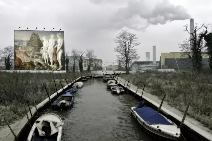 Inscape 083 Un paysage de friche industrielle traversé par un canal vénitien avec, sur la gauche, un énorme panneau publicitaire représentant le mélange deux peintures du seizième siècle. La Destruction de Troie et le Jugement de Pâris avec La Tour de Babel.